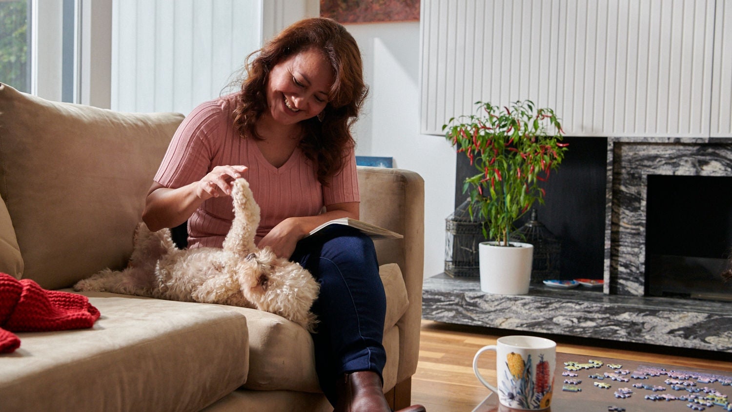 Middle-aged woman playing with her dog on the sofa